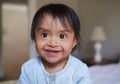 Happy, portrait smile and Down syndrome baby relaxing on a bed in happiness at home. Cheerful little child with genetic Royalty Free Stock Photo