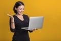 Happy Portrait smiling young asian woman holding laptop isolated on yellow background , Beautiful asian female holding notebook Royalty Free Stock Photo