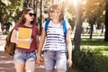 Happy positive attractive female students lesbians hold hands together, carry rucksacks, have friendly talk, speak about universit