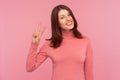 Happy positive brunette woman showing v sign, satisfied with her victory looking at camera with toothy smile, success