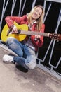 Happy Positive Caucasian Blond woman Posing in Red Leather Jacket and Jeans with Guitar Outdors Royalty Free Stock Photo