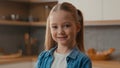 Happy positive portrait at home cheerful carefree Caucasian cute 10s little girl at kitchen smiling toothy looking Royalty Free Stock Photo