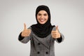 Joyful hijab-wearing woman giving thumbs up in suit Royalty Free Stock Photo