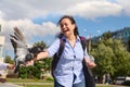 Happy positive smiling multi- ethnic positive young woman feeding pigeons on the square on a sunny spring day Royalty Free Stock Photo