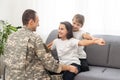 happy positive smiling soldier man in camouflage sitting with his daughter on sofa, looking how his kid grown when he Royalty Free Stock Photo