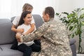 happy positive smiling soldier man in camouflage sitting with his daughter on sofa, looking how his kid grown when he Royalty Free Stock Photo