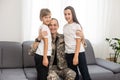 happy positive smiling soldier man in camouflage sitting with his daughter on sofa, looking how his kid grown when he Royalty Free Stock Photo