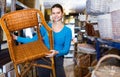 Young customer woman standing with wicker chair in shop for decor Royalty Free Stock Photo