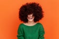 Happy positive woman with Afro hairstyle wearing green casual style sweater showing tongue out Royalty Free Stock Photo