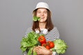 Happy positive woman holding vegetables isolated over gray background biting lettuce keeps green diet feel healthy enjoying Royalty Free Stock Photo