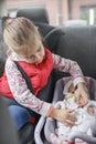 Girl sitting in car seats and playing with doll which also in car seat, child transportation safety Royalty Free Stock Photo