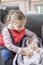 Girl sitting in car seats and playing with doll which also in car seat, child transportation safety Royalty Free Stock Photo