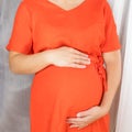 happy pregnancy concept. pregnant woman in red dress holding her hands on her belly Royalty Free Stock Photo