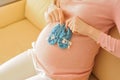 Happy pregnancy sitting on sofa at home with bootees. Royalty Free Stock Photo