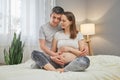 Happy pregnancy time. Caucasian young delighted pregnant woman and her husband spending time together in bed couple hugging each Royalty Free Stock Photo