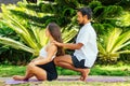 Happy pregnancy wife and asian husband doing couple meditation in green park by sea beach