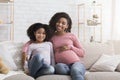 Happy pregnant african woman and her little daughter relaxing at home Royalty Free Stock Photo