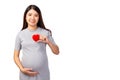 Happy pregnant asian woman holding red heart and touching her abdomen with smile face, isolated on white background and copy space Royalty Free Stock Photo