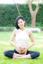 Happy pregnant beautiful young asian woman with gesture hand heart shape in the park. Royalty Free Stock Photo