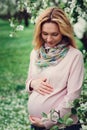 Happy pregnant blonde beautiful woman walking outdoor in spring park or garden Royalty Free Stock Photo