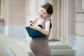 Happy pregnant business woman talking on phone and writing notes Royalty Free Stock Photo