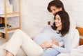 Happy pregnant couple hugging and relaxing on bed at home Royalty Free Stock Photo