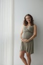 Image of happy pregnant woman touching her big belly, looking at camera, smiling. Waiting for the baby. Motherhood.