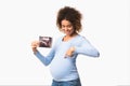 Happy pregnant lady showing ultrasound scans and pointing at belly Royalty Free Stock Photo