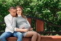 Happy pregnant woman, family couple in the park, green floral background. In anticipation of a miracle, a child. Family life, Royalty Free Stock Photo