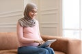 Happy Pregnant Muslim Woman Using Digital Tablet Sitting At Home Royalty Free Stock Photo