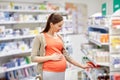 Happy pregnant woman choosing medicine at pharmacy