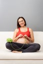 Happy pregnant woman is crocheting