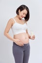 Happy pregnant woman drinking a glass of fresh milk and touching her belly Royalty Free Stock Photo