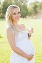 Happy pregnant woman drinking water from a glass in park Royalty Free Stock Photo