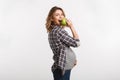 happy pregnant woman eating apple and smiling at camera