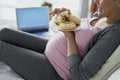 Happy pregnant woman eating donuts in bed Royalty Free Stock Photo