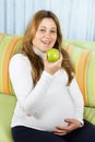 Happy pregnant woman eating a green apple Royalty Free Stock Photo