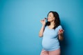 Happy pregnant woman eating strawberries on blue background. Balanced diet during pregnancy. Maternity health concept Royalty Free Stock Photo