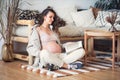 happy pregnant woman flips through a magazine while sitting on the floor