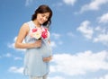 Happy pregnant woman with flowers touching belly Royalty Free Stock Photo