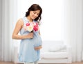 Happy pregnant woman with flowers touching belly Royalty Free Stock Photo