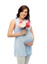 Happy pregnant woman with flowers touching belly Royalty Free Stock Photo