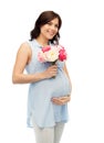 Happy pregnant woman with flowers touching belly Royalty Free Stock Photo