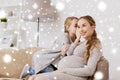 Happy pregnant woman and girl gossiping at home Royalty Free Stock Photo