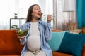 Happy pregnant woman with great appetite eats vegetable salad sitting on sofa healthy food self-care Royalty Free Stock Photo