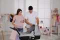 Happy pregnant woman with her husband choosing baby stroller in store. Shopping concept Royalty Free Stock Photo