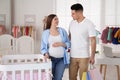 Happy pregnant woman and husband with shopping bags choosing crib in store Royalty Free Stock Photo