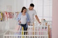 Happy pregnant woman and her husband with shopping bags choosing crib in store Royalty Free Stock Photo