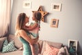 Happy pregnant woman with her toddler daughter at home