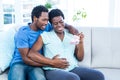 Happy pregnant woman holding baby shoes while sitting on sofa Royalty Free Stock Photo